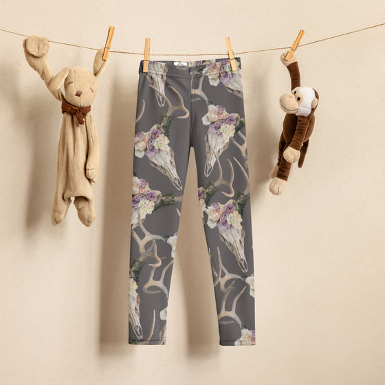 Kids Leggings with deer skulls and antlers on them from River to Ridge Clothing brand hanging on a closeline with toys for toddlers