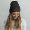 River to Ridge Logo stitched on a beanie. Logo is gold with mountains worn by a woman looking down