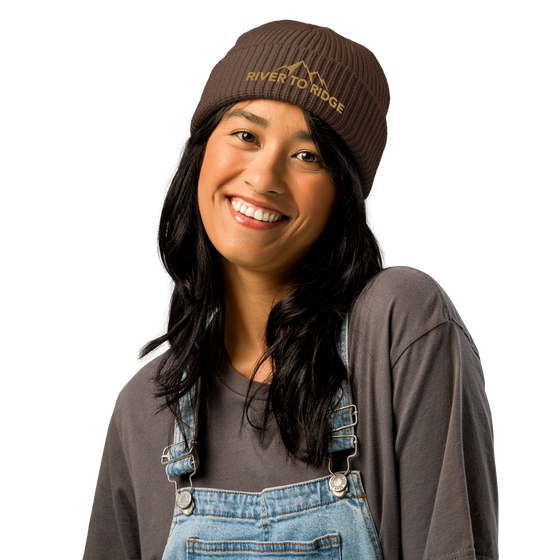 Product mockup of a fisherman's style skull cap beanie from River to Ridge Clothing Brand with the mountain logo on it worn by a woman with long hair