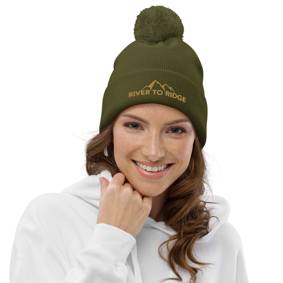 Product mockup of River to Ridge Brand Knit Hat with pom pom worn by a red head woman