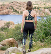 Woman hiking in the watson lake park in prescott arizona in the red rocks wearing a matching camo flag sports bra and compression leggings and tennis shoes