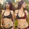 Beautiful woman with tattoos wearing a reversible bikini one side with a camo flag pattern and the other side with a red blue and black patriotic gun pattern, from the brand River to Ridge