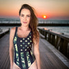 Woman on the boardwalk in florida wearing a camo flag one piece patriotic outdoors swimsuit for river to ridge outdoors