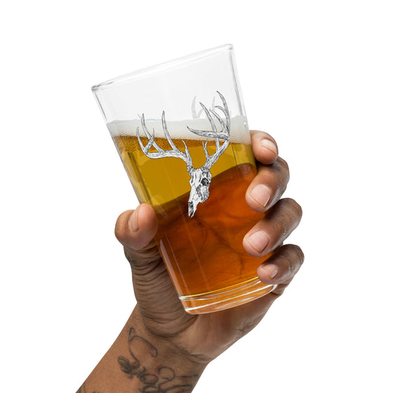 Product mockup of a pint beer glass with whietail deer skull logo from River to Ridge clothing brand