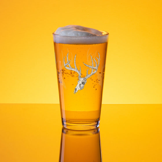 Product mockup of a pint beer glass with whietail deer skull logo from River to Ridge clothing brand