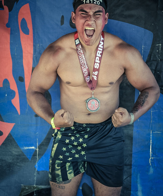 Man in Spartan Race with Medal and wearing Mens Gym Shorts with Camo American Flag Pattern from River to Ridge Clothing Brand