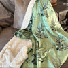 Elk Logo Sherpa Fleece Blanket  from River To Ridge Brand in green with ivory fleece backing, on a couch