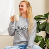 woman drinking coffee wearing a river to ridge clothing brand sweatshirt with an elk on it in grey