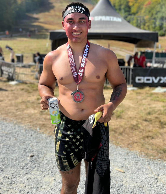 Man in Spartan Race with Medal and wearing Mens Gym Shorts with Camo American Flag Pattern from River to Ridge Clothing Brand