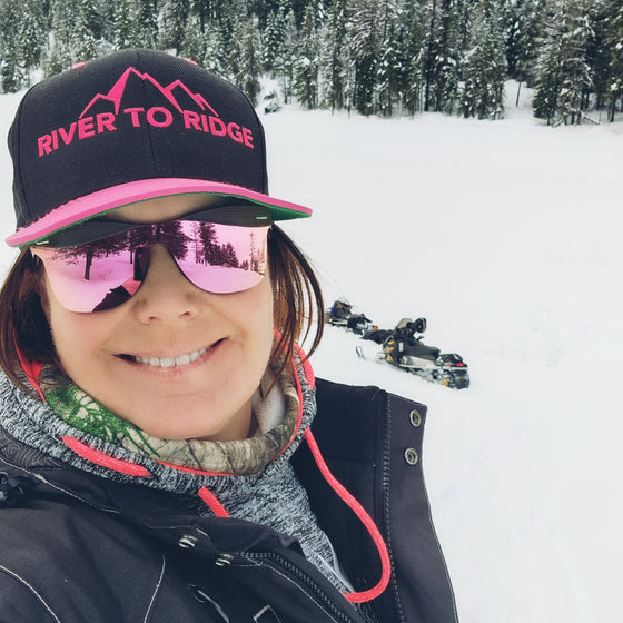 Woman wearing River to Ridge hot pink and black flatbill hat outside in the snow