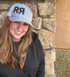 River to Ridge Logo R to R trucker hat in grey with white mesh back - worn by a red head woman in a black coat outdoors