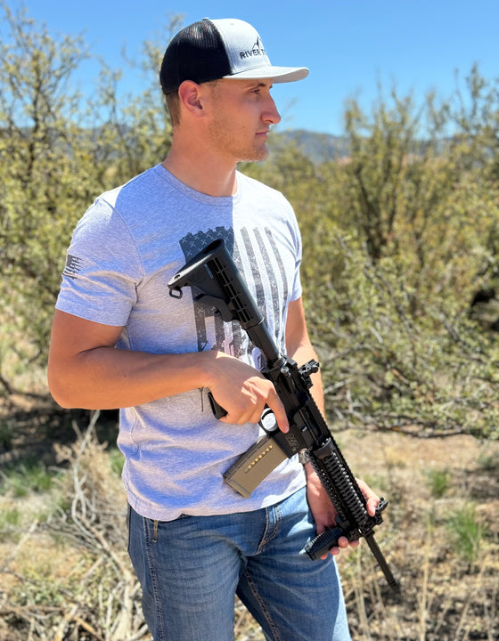 Man wearing a tactical logo T shirt in grey outdoors from River to Ridge clothing brand