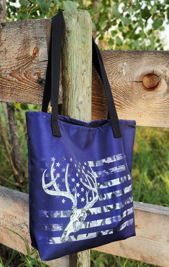 Whitetail Flag Antler Logo purple tote bag from River to Ridge Clothing Brand hanging on a fence