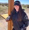 Woman wearing turkey strut hoodie and River to Ridge Clothing Brand hat. Hoodie has turkey's on the sleeves and hood and a black center.