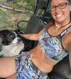 Woman wearing turkey feather pattern athletic shorts in a side by side 4x 4 offroad vehicle with her dog and wearing a sports bra from River to Ridge Clothing Brand