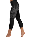 Legs of a woman wearing black capri leggings with an elk deer red stag on them in grey 