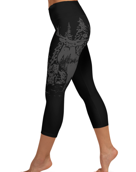 Legs of a woman wearing black capri leggings with an elk deer red stag on them in grey 