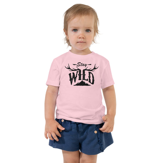 toddler in pink T shirt with stay wild logo and antlers and mountain 