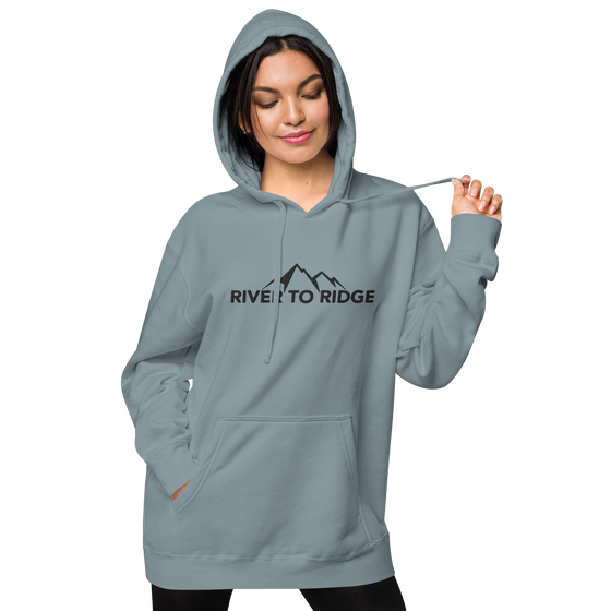 Indigo Blue Womens Hoodie with the River to Ridge Clothing Mountain Logo embroidered on the chest and cuff of sleeve. worn by a pretty woman with the hood up