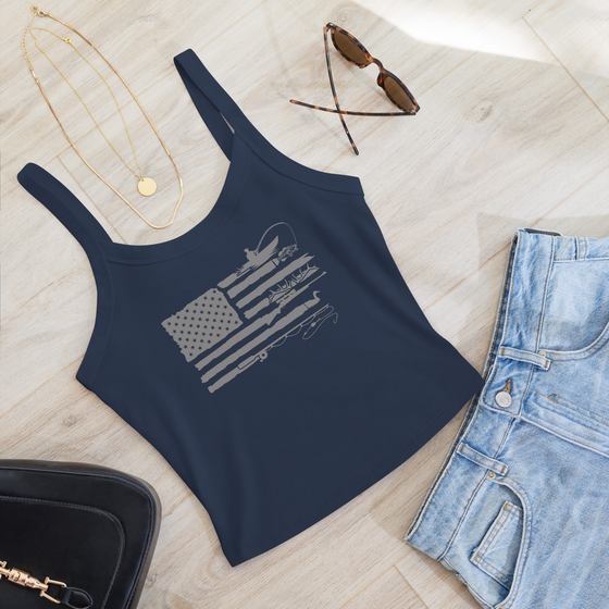 River to Ridge Brand Womens tank top in blue with the Sportsmans Flag Logo on it in grey, featuring the USA flag and antlers, fishing, bass, ducks, rifle; outdoors themes in the stripes. Laid out with jeans and a necklace and glasses